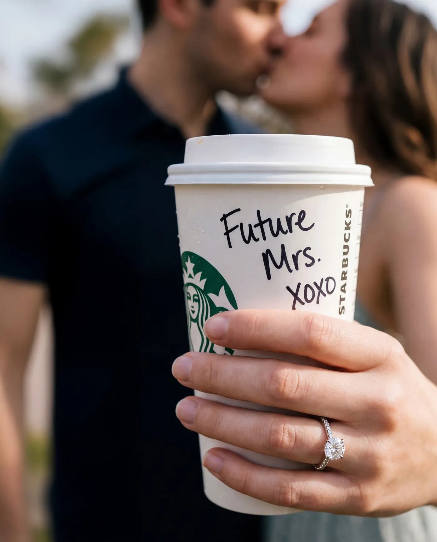 Round engagement ring on a hand holding a Future Mrs. coffee cup